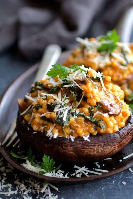 Photo of Barley Risotto Stuffed Portobello Mushrooms garnished with parsley and Parmesan cheese.