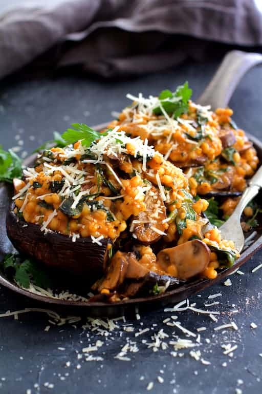 Photo of Barley Risotto Stuffed Portobello Mushrooms with a fork taking some of the stuffing off the mushroom.