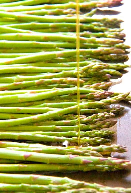 Photo of asparagus being drizzled with oil.