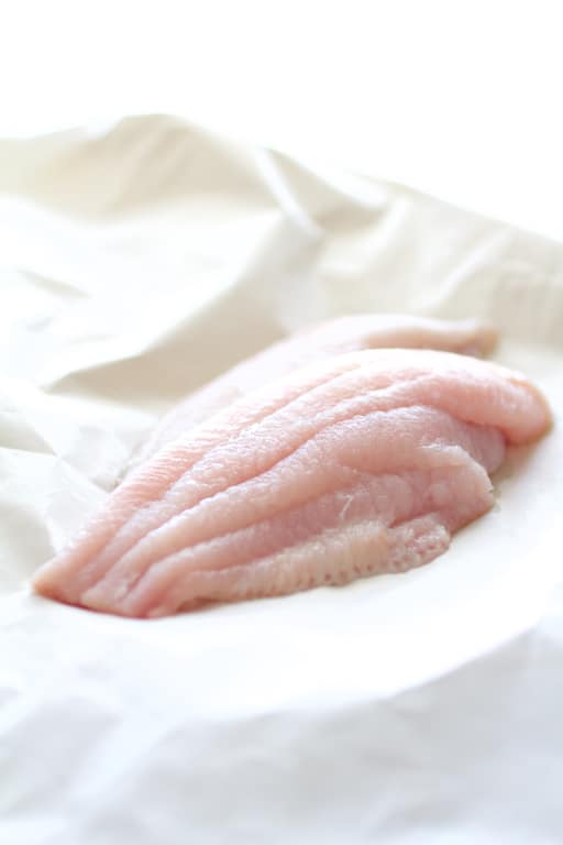 Photo of fresh catfish fillets on white butcher paper before being coated and baked.