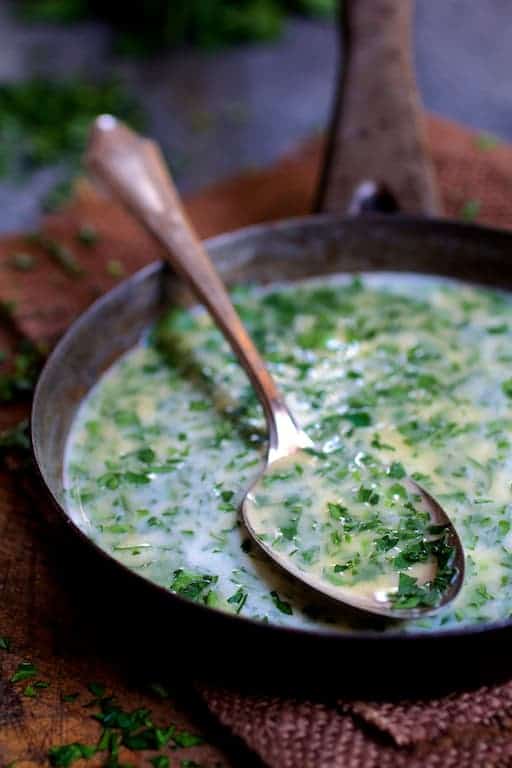 Photo of melted butter in small saucepan with some on a spoon.