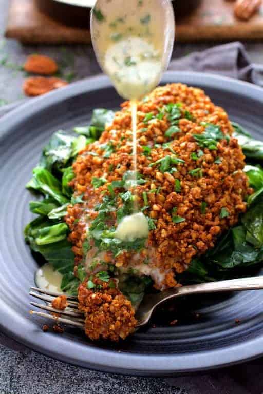 Baked Catfish Pecan Meuniere with butter being drizzled over a piece.