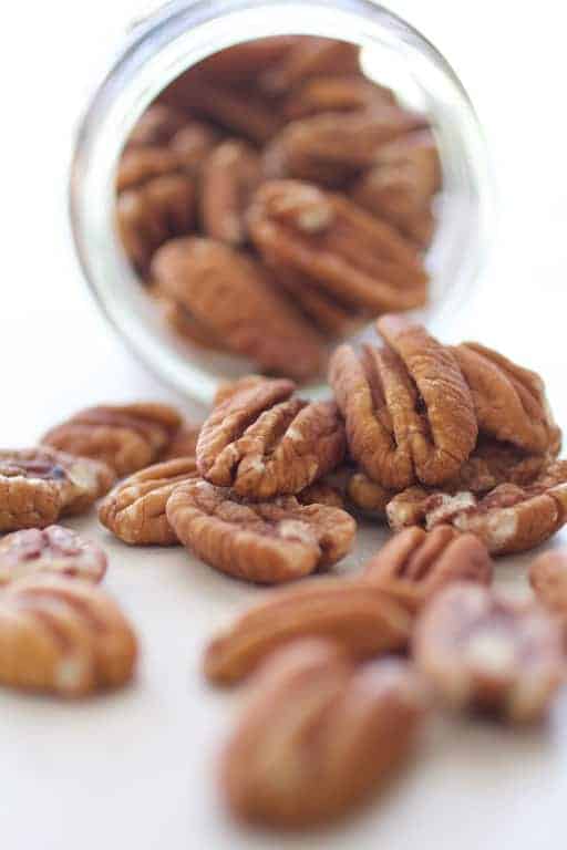 Photo of pecans spilling out of glass jar.