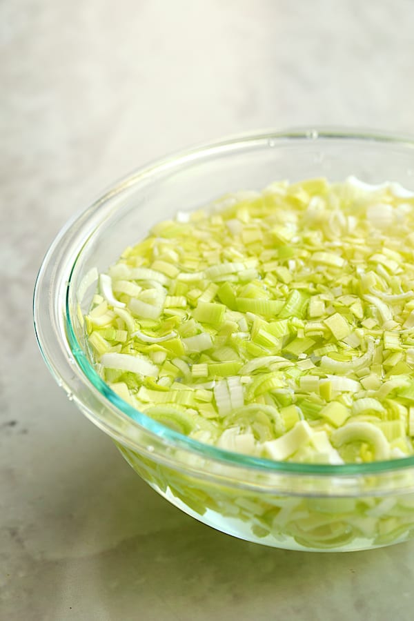 Photo of cut leeks in water in glass bowl.