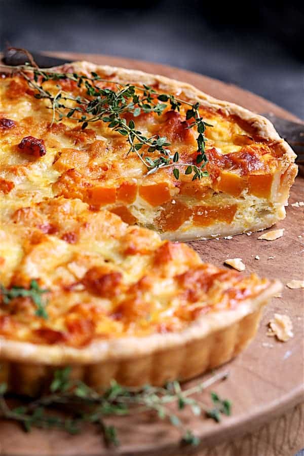 Close-up photo of Butternut Squash Leek and Gruyere Tart with piece removed exposing interior of the tart.