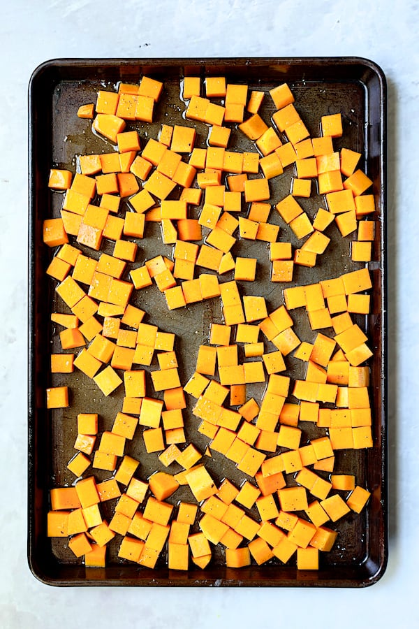 Photo of cubed butternut squash on baking sheet before being roasted.