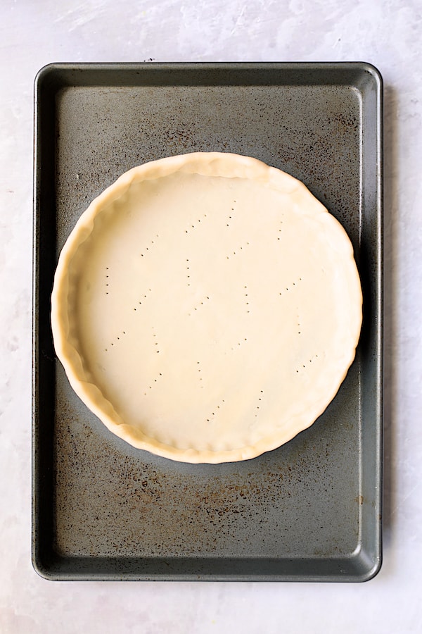 Photo of unbaked tart crust in tart pan on baking sheet.