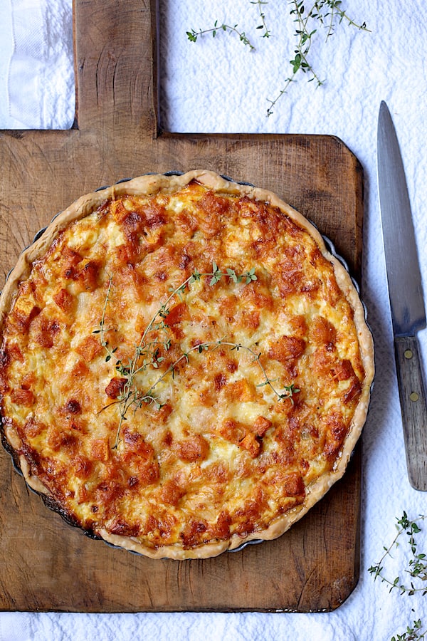 Photo of baked Butternut Squash Leek and Gruyere Tart on wood board.