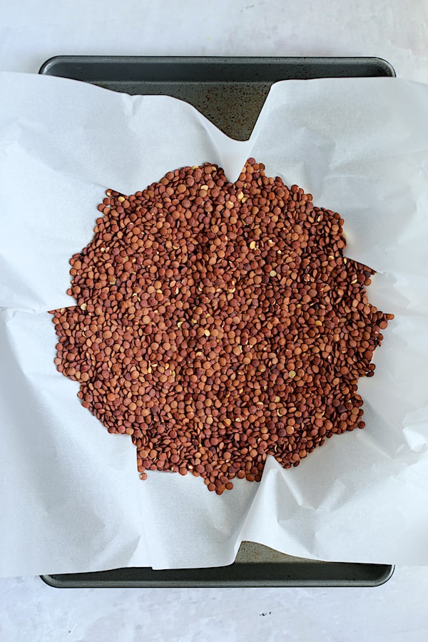 Photos of lentils on parchment paper inside unbaked crust.