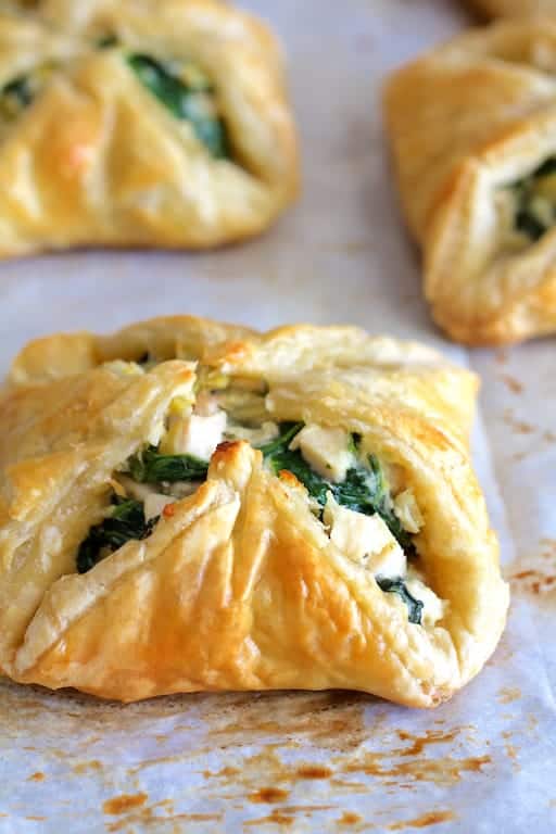 Close-up photo of Chicken Spinach and Artichoke Puff Pastry Parcels on parchment paper.