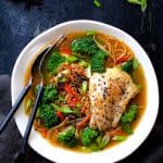 Asian Vegetable and Noodle Broth Bowls with Pan-Seared Fish in white bowl with fork and spoon.