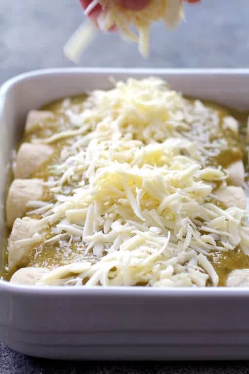 Photo of cheese being sprinkled over enchiladas.