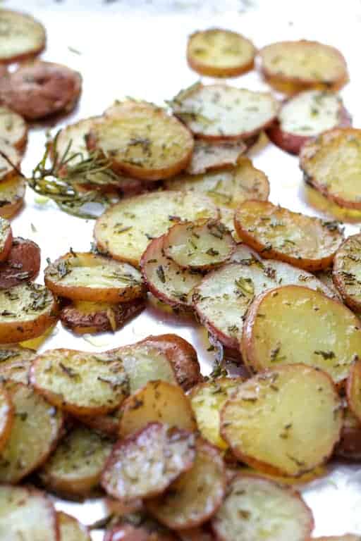 Photo of thinly sliced roasted potatoes with rosemary.