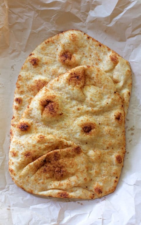 Photo of two pieces of naan bread on parchment paper.