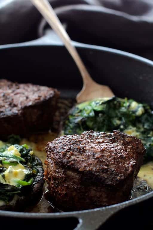 Process photo of Beef Tenderloin Fillets with Spinach Cambozola Stuffed Mushrooms being cooked together in cast iron skillet.