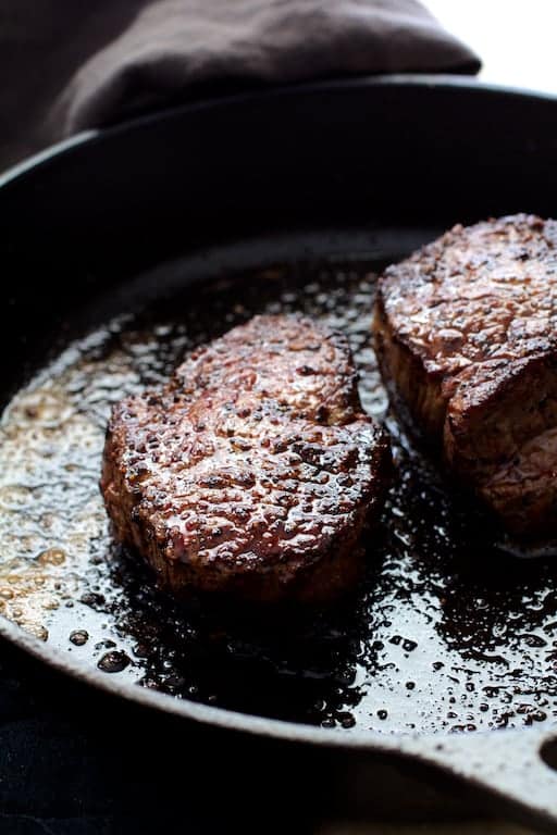 Photo of two seared beef fillets in cast iron skillet.