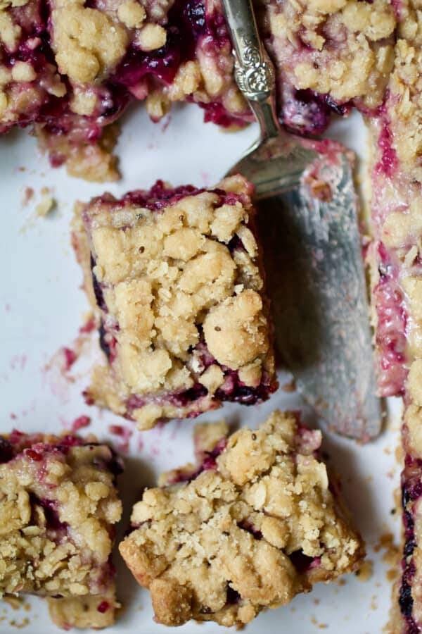 Photo of Blueberry Crumble Bars in white baking dish with serving utensil.