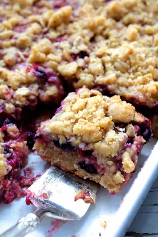 Close-up photo of Blueberry Crumble Bars with one bar being removed with silver pie server.