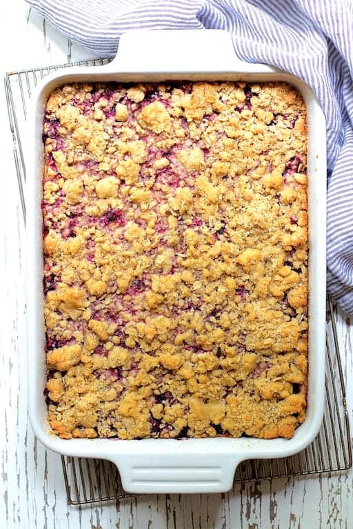 Photo of Blueberry Crumble Bars in white baking dish on cooling rack before being cut.