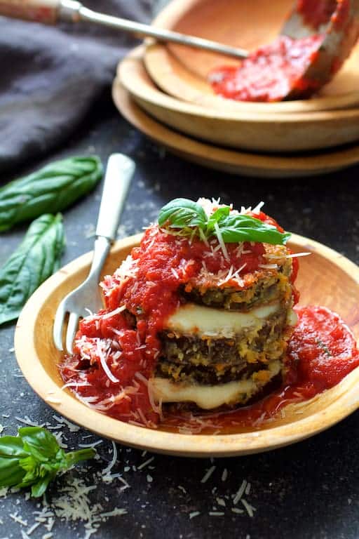 Photo of Eggplant Parmesan Stacks in wooden bowl after being sauced and garnished with fresh basil.