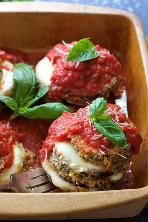 Eggplant Parmesan Stacks in earthenware baking dish being lifted out with fork.