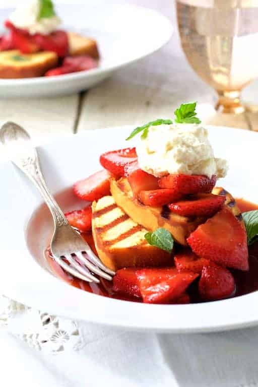 Grilled Pound Cake with Balsamic Mascerated Strawberries and Mascarpone Cream on white plate with fork.