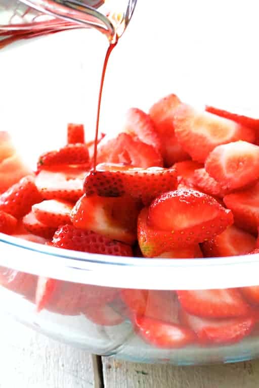 Photo of balsamic vinegar being poured over strawberries.