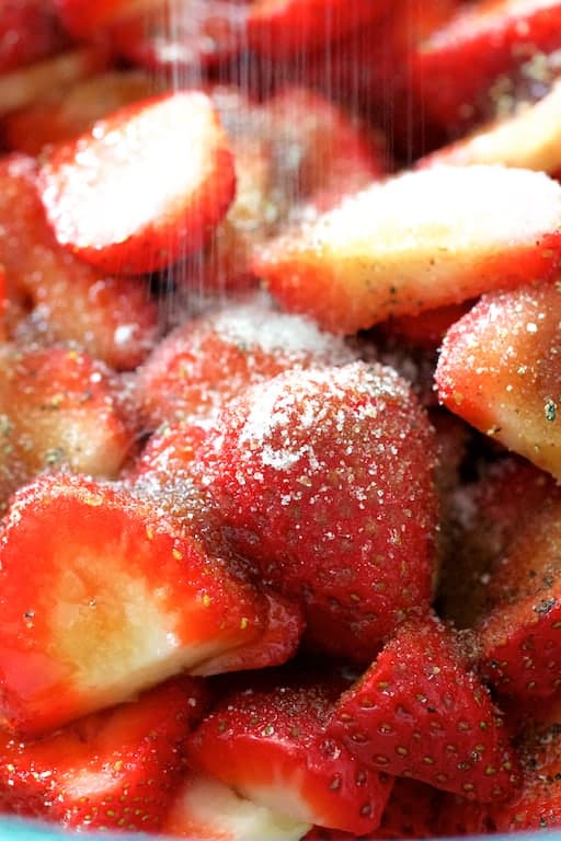 Close-up photo of strawberries being sprinkled with sugar.