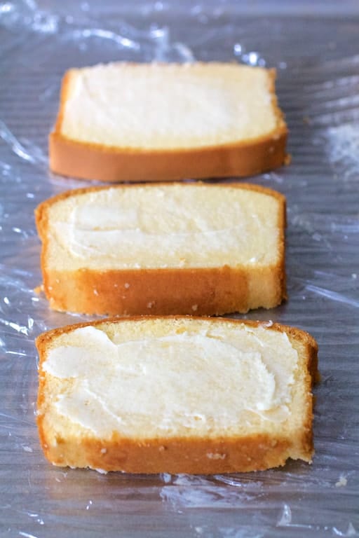 Photo of buttered pound cake slices on plastic wrap ready to be grilled.
