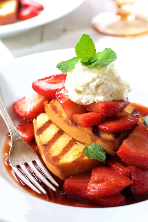 Photo of Grilled Pound Cake with Balsamic Macerated Strawberries and Mascarpone Cream garnished with mint sprig.