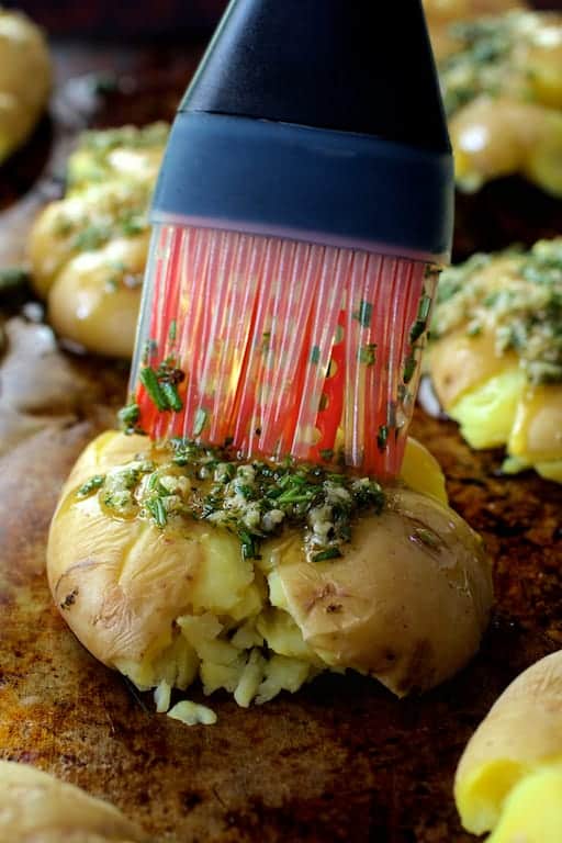 Photo of potatoes being brushed with rosemary garlic infused oil with silicone brush.