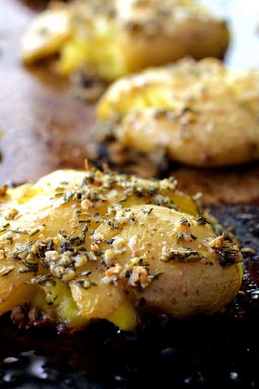 Close-up photo of Rosemary Garlic Crushed Potatoes on baking sheet.