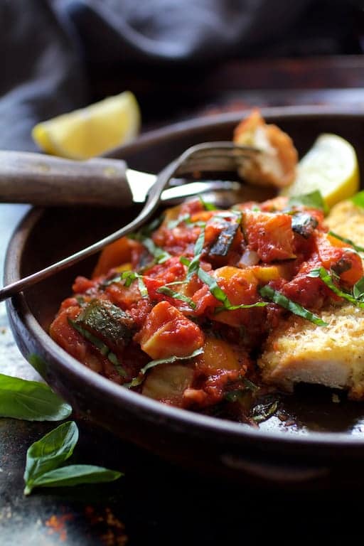 Photo of the ratatouille in clay dish with fork and knife.