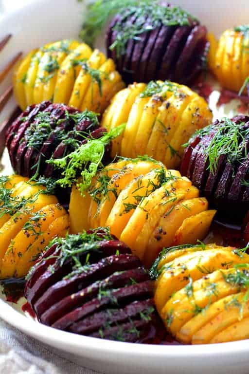 Photo of Roasted Hasselback Beets with Dill Dressing in white serving dish garnished with fresh dill.