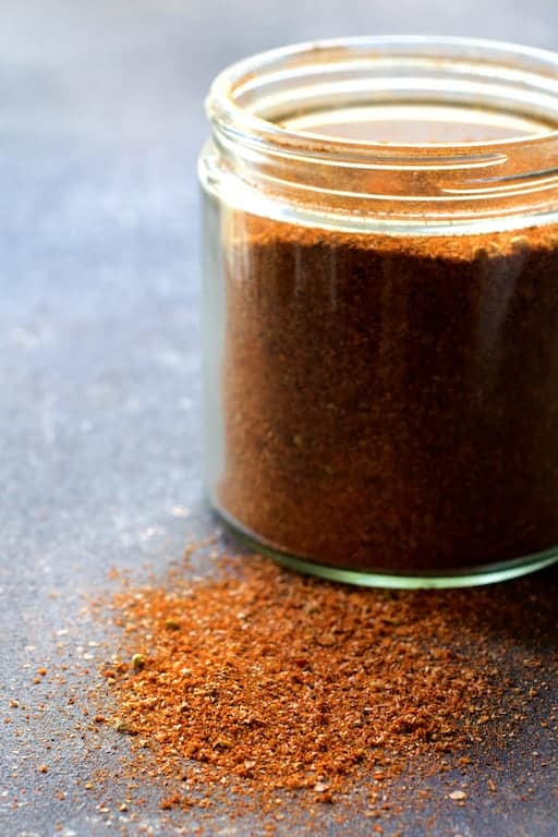 Photo of spice rub in glass jar with some on the surface.