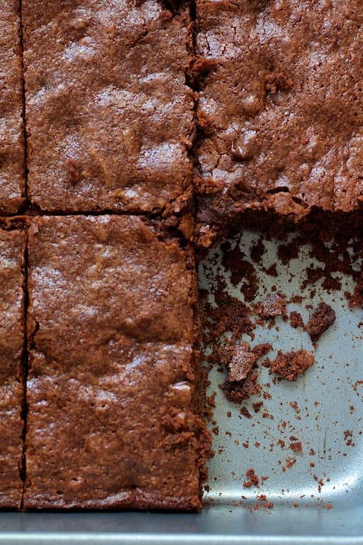 Close-up photo of Whole Wheat Ancho Chili Brownies in pan with one piece missing showing crumbs.