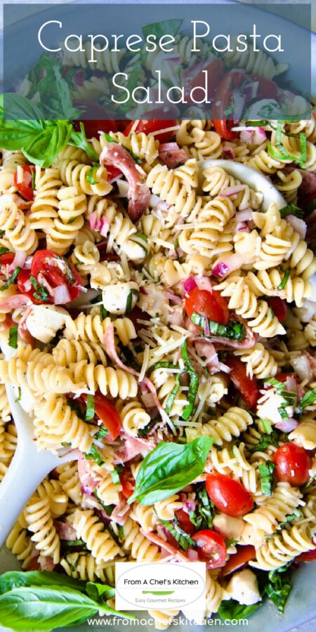 Pinterest graphic for Caprese Pasta Salad showing it in a in blue bowl being stirred with serving utensils.