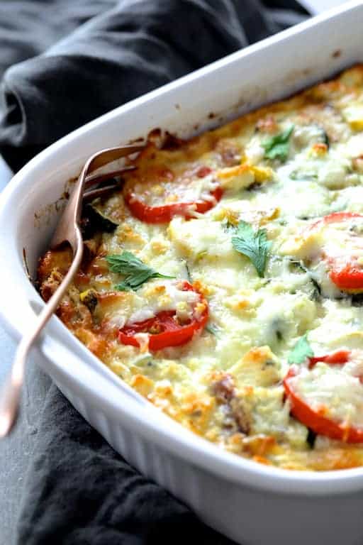 Photo of Four Cheese Strata with Zucchini and Tomatoes on gray towel with serving fork.