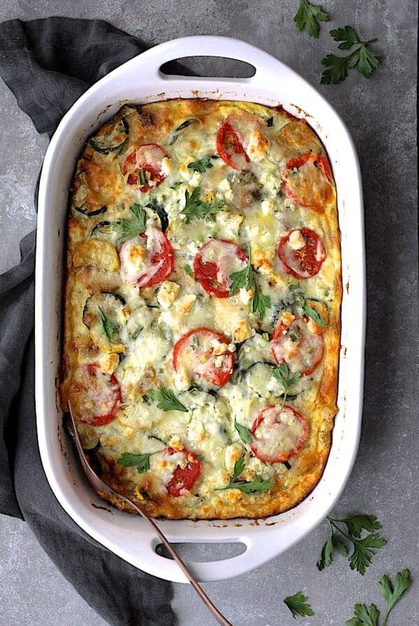 Four Cheese Strata with Zucchini and Tomatoes in white rectangular baking dish.
