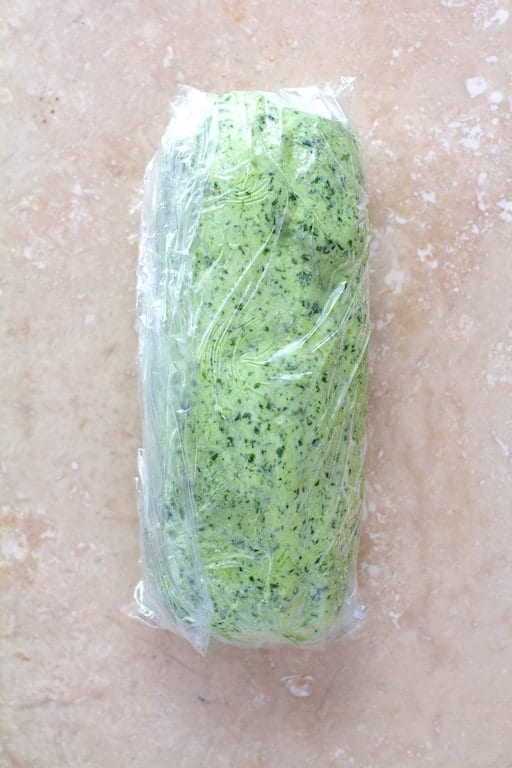 Photo of avocado butter rolled into a cylinder in plastic wrap.