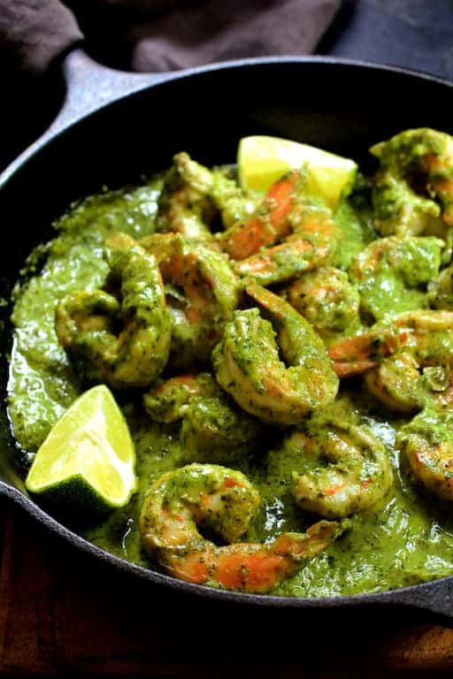 Photo of Shrimp in Avocado Butter in cast iron skillet garnished with lime wedges.
