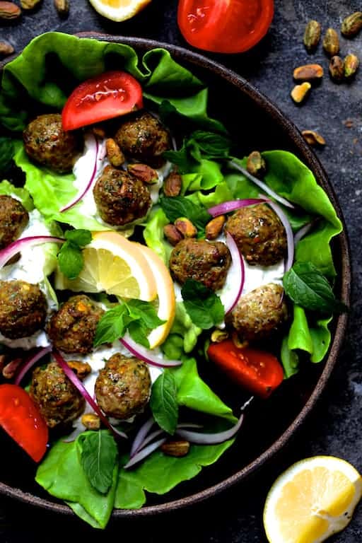 Photo of Turkish Turkey Meatball Lettuce Wraps with Tzatziki in clay dish with all the garnishes.