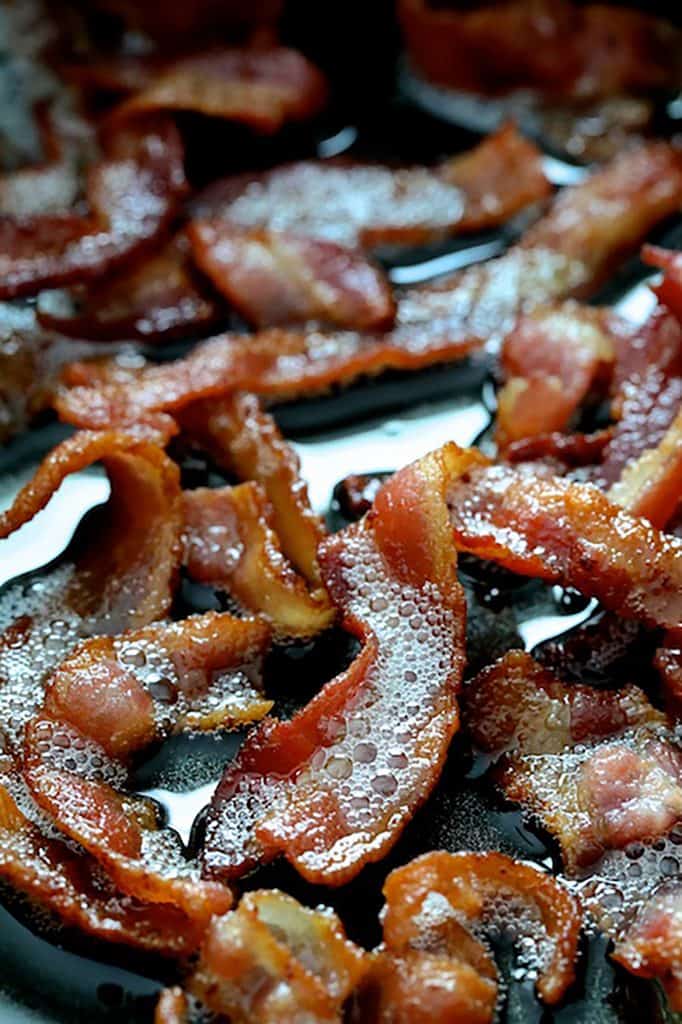 Photo of bacon simmering away in saute pan.