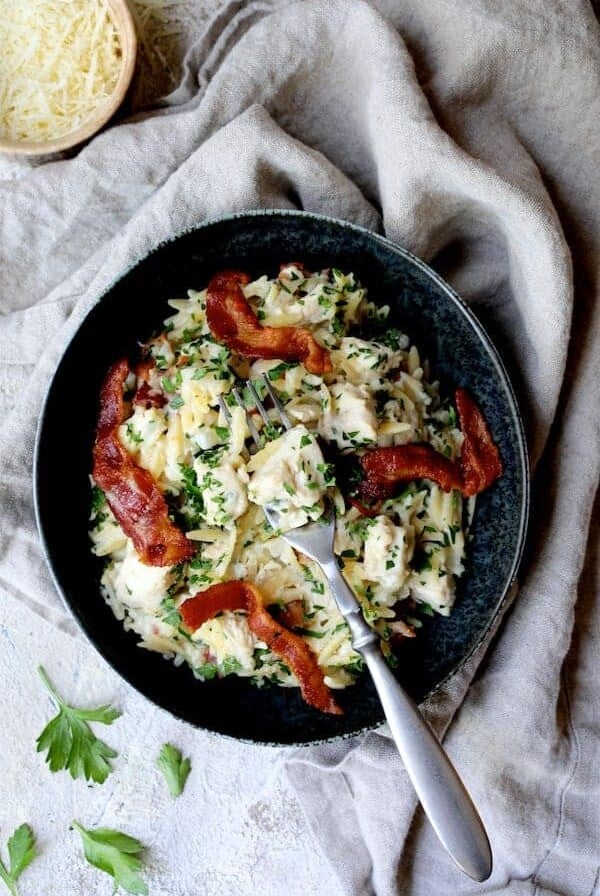 Creamy One Pot Chicken and Orzo Risotto with Bacon in black bowl.