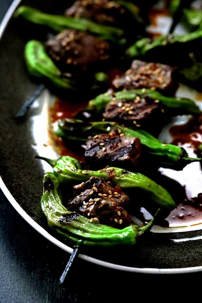 Close-up photo of Japanese Beef and Shishito Pepper Skewers on gray-rimmed platter.
