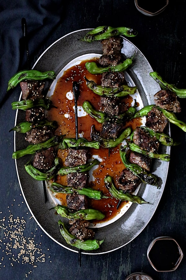 Photo of Japanese Beef and Shishito Pepper Skewers on gray-rimmed platter.