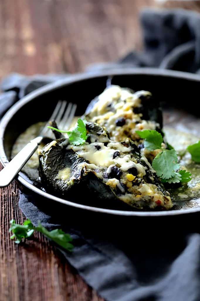 Photo of Quinoa Corn and Black Bean Stuffed Poblano Peppers in dish on gray napkin garnished with cilantro.
