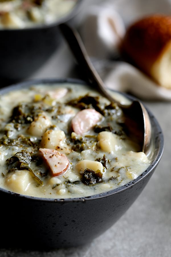 Close-up photo of Creamy Potato Kielbasa and Kale Soup in gray bowl.