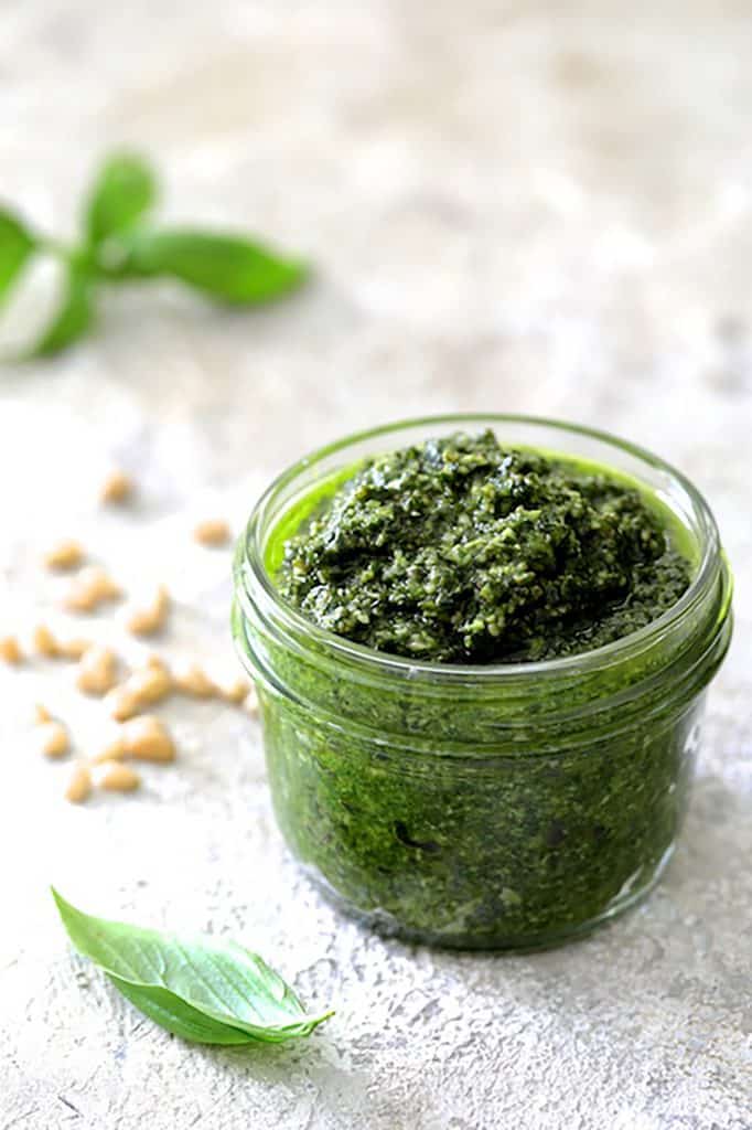 Photo of pesto in pint-sized Mason jar on white background.