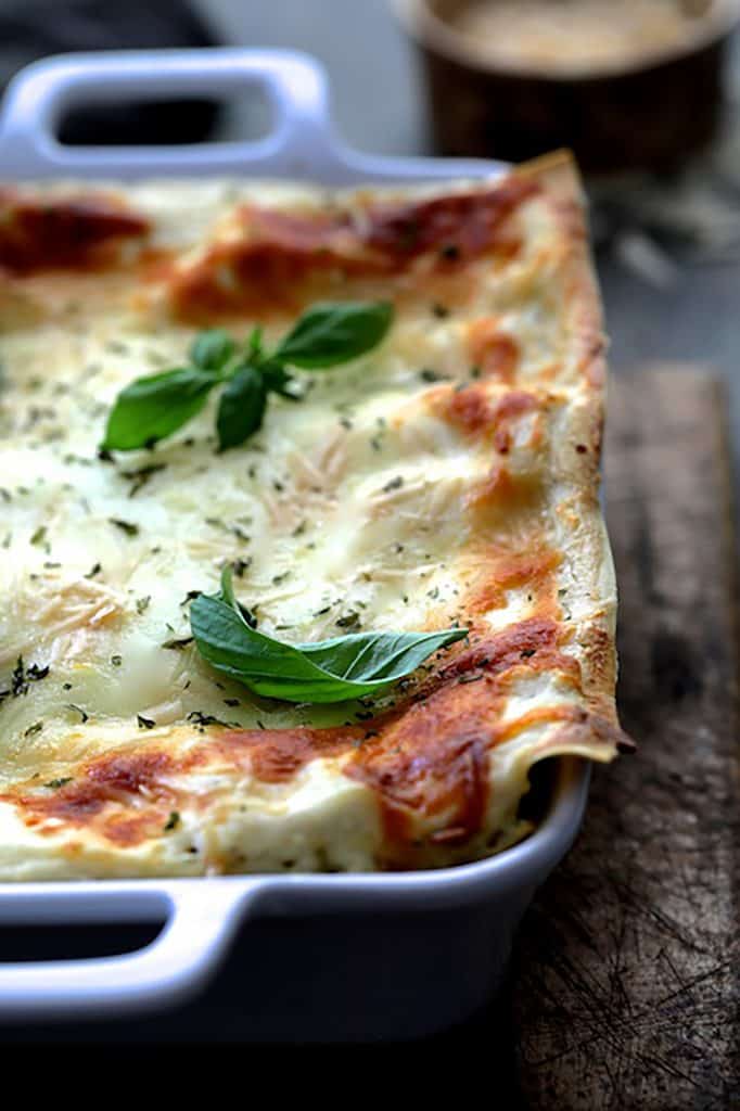 Close-up photo of Lasagna with Pesto Green Beans and Potatoes in white baking dish.